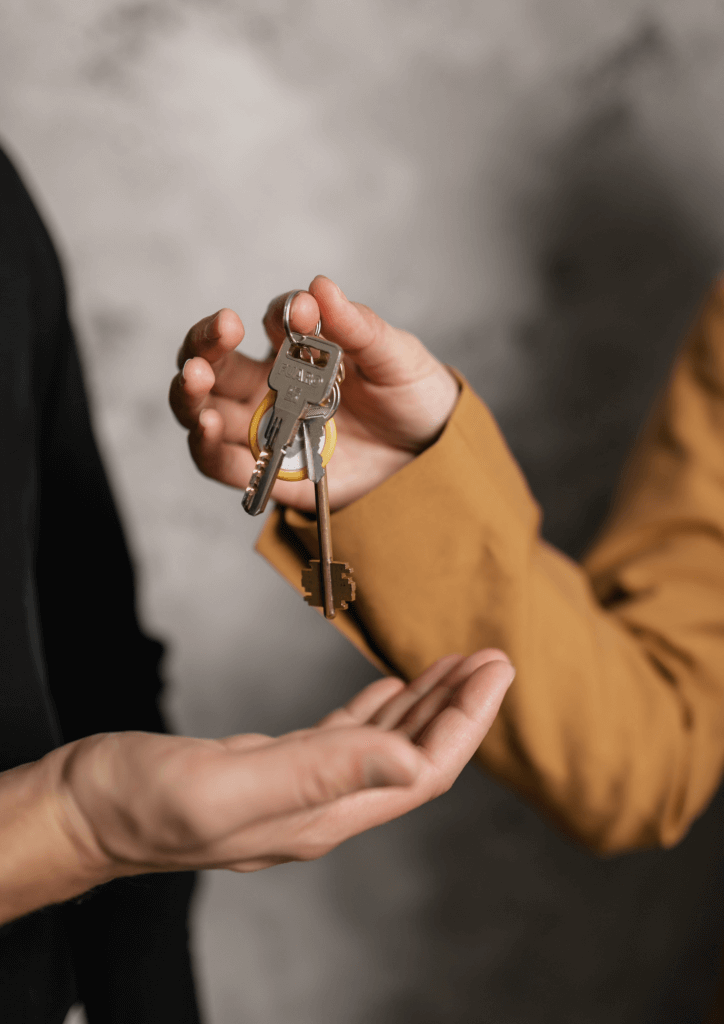 Photo du bras d'une personne donnant les clés d'un appartement à une autre main tendue